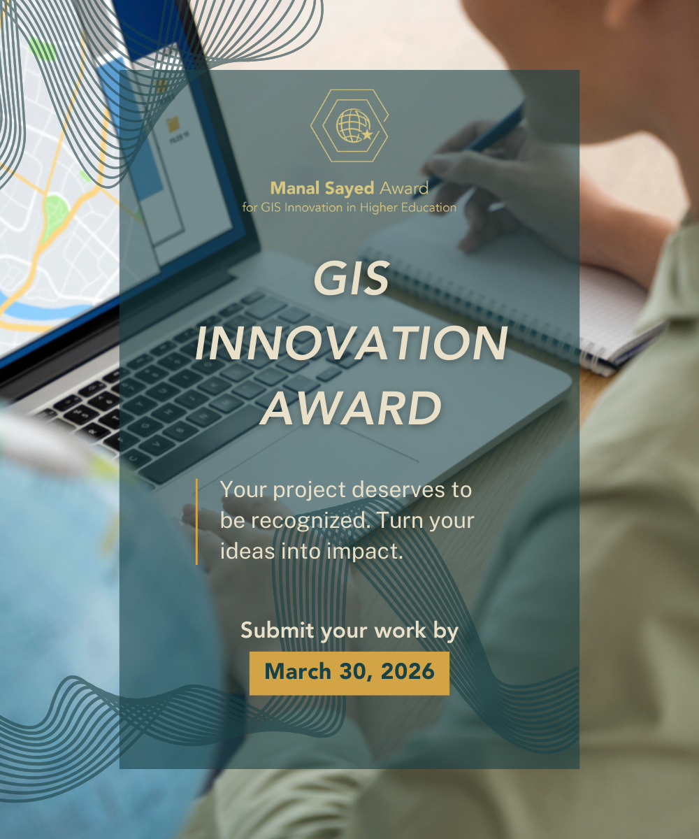 Jack Dangermond wearing a gray suit and round framed glasses during his Plenary Session presentation with colorful maps behind him.